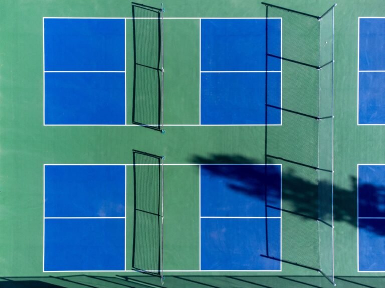 Top-down photo of vibrant blue and green sports courts with nets, perfect for recreational activities.